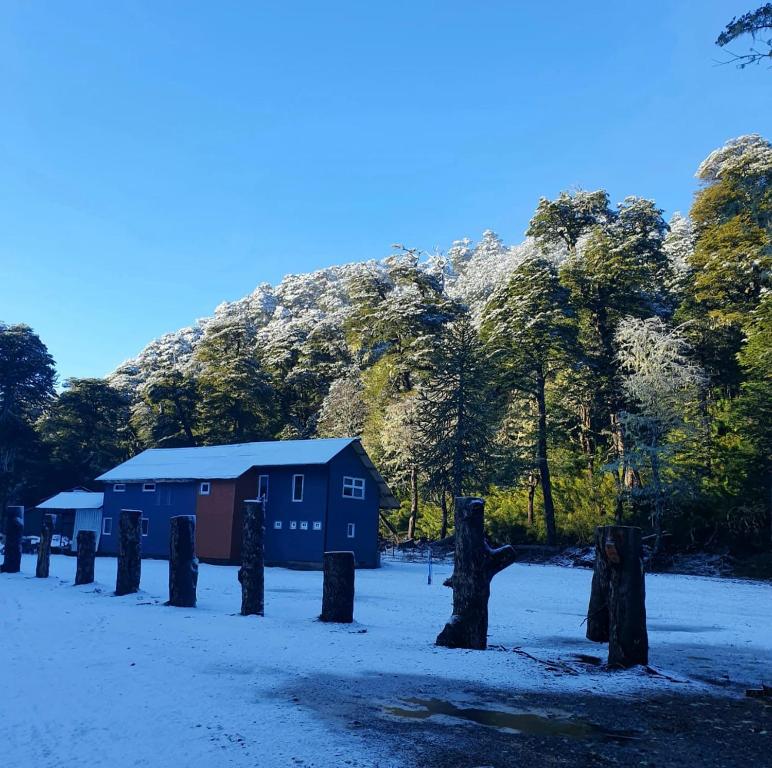 una casa en medio de un campo con una montaña en Refugio de Montaña Sollipulli, Lodge Nevados de, en Melipeuco