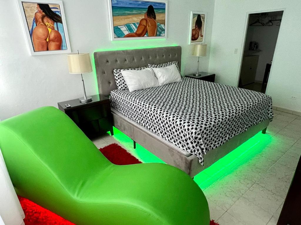 een slaapkamer met een bed en een groene stoel bij Beachfront Tropical Tantra Apartment in San Juan