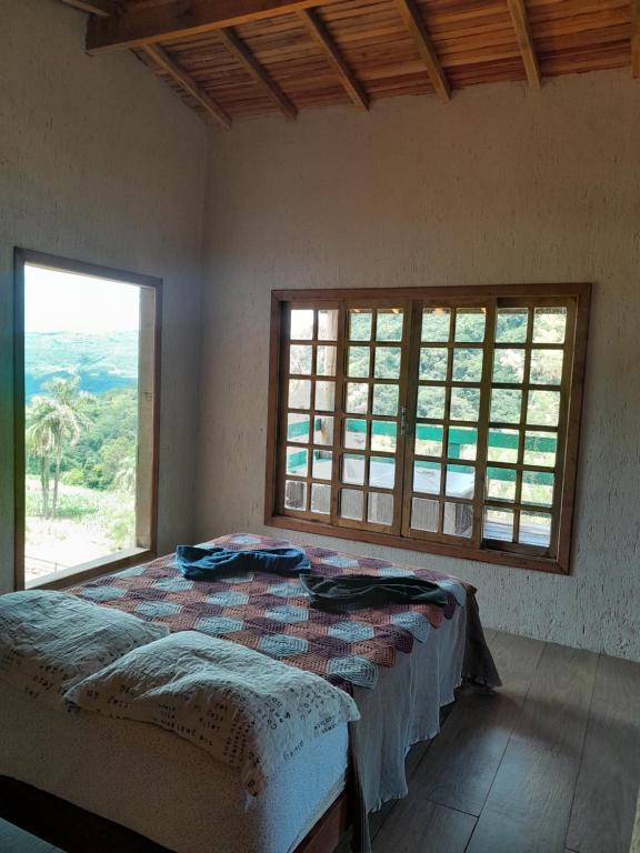 um quarto com uma cama e uma grande janela em Chácara paraíso dá paz em Nova Petrópolis