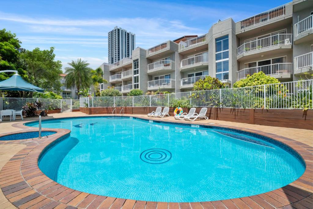 a swimming pool with chairs and a building at Markham Court in Gold Coast