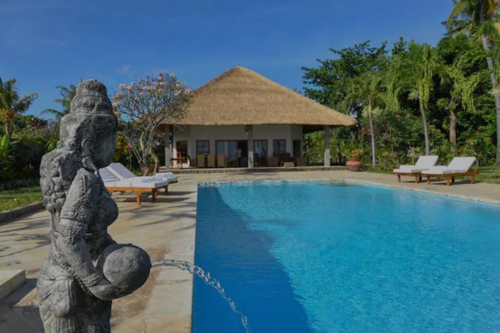 une statue à côté de la piscine d'un complexe dans l'établissement Beachfront Private VILLA & POOL, à Banjar