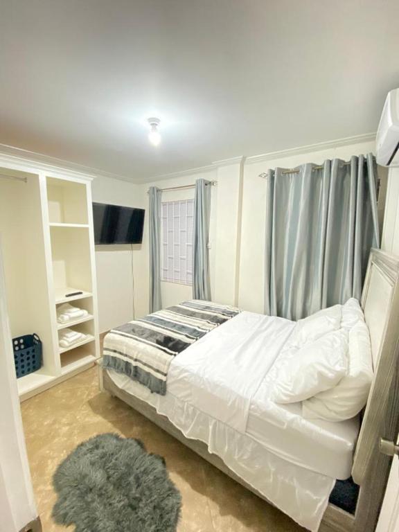 een slaapkamer met een wit bed en een raam bij Kelly's Apartments - Rental near Airport, Amenities and Bus Route in Saint Philip