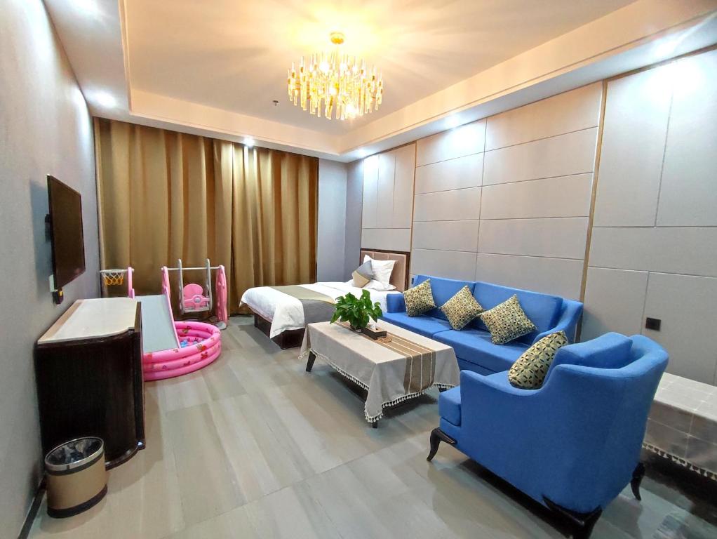 une chambre d'hôtel avec un lit et un canapé bleu dans l'établissement Zhangye Kerry Hotel, à Zhangye