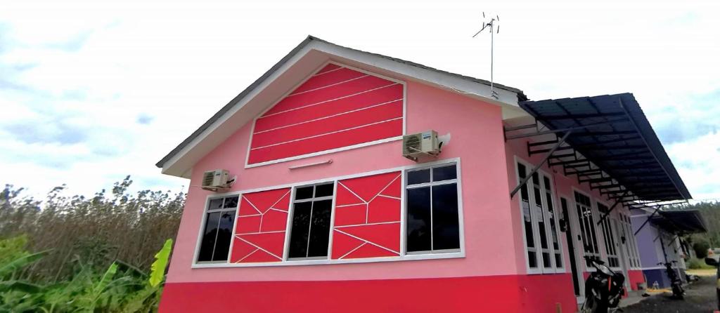 uma casa cor-de-rosa com um telhado vermelho em Az HOMESTAY PENDANG KEDAH em Pendang