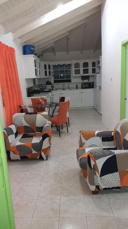 a living room with orange chairs and a kitchen at El Palacio Apartments in Bridgetown