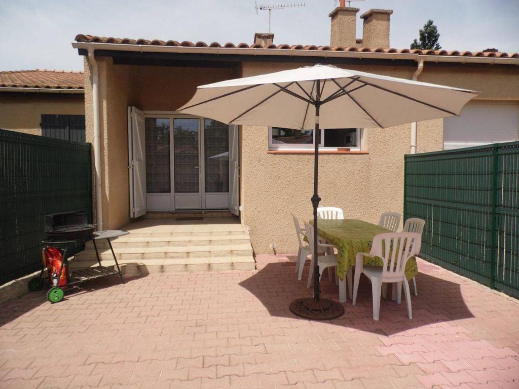 un patio avec une table, des chaises et un parasol dans l'établissement Maison avec Jardin, Centre-Ville, Proche Plage, 6 Pers. - FR-1-701-50, à Valras-Plage