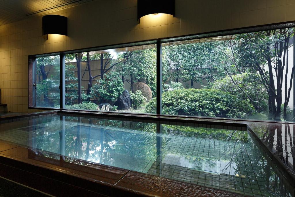 a swimming pool in a building with a large window at Mitsui Garden Hotel Kyoto Sanjo in Kyoto
