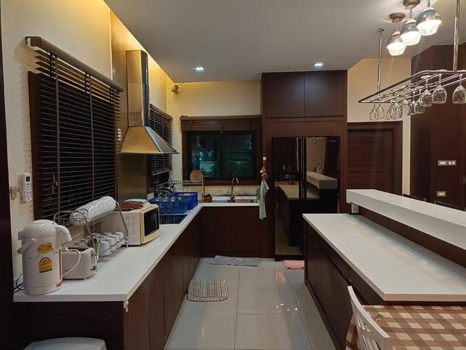 una cocina con armarios de madera y encimeras blancas en Eco stay - Luxury pool + Seaview Villa en Pattaya North
