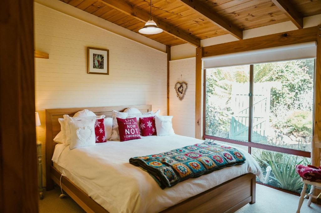 Fleurty's Point Cottage at Franklin South, Huon Valley, Tasmania في Franklin: غرفة نوم بسرير كبير ومخدات حمراء