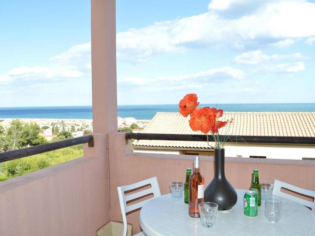 une table avec un vase de fleurs sur un balcon dans l'établissement Studio Cabine avec Piscine, 4 couchages, proche plage et commerces - FR-1-229D-345, à Saint Pierre La Mer