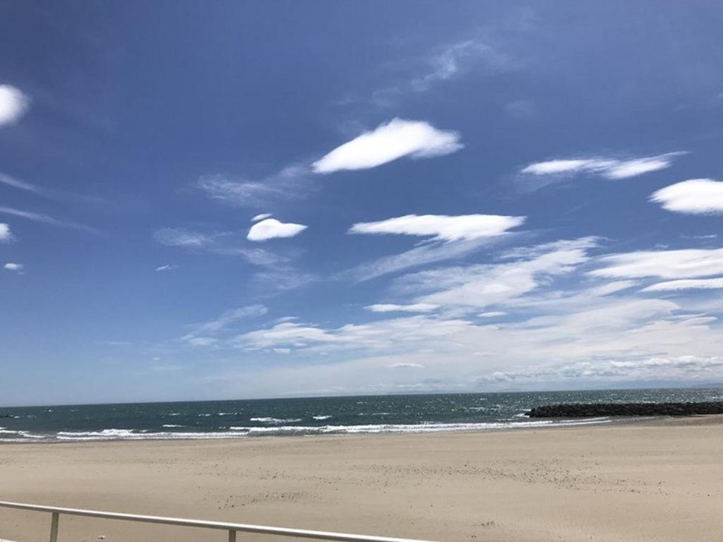uma praia com um céu azul e o oceano em Studio Le Grau d'Agde, 1 pièce, 4 personnes - FR-1-423-26 em Le Grau-dʼAgde