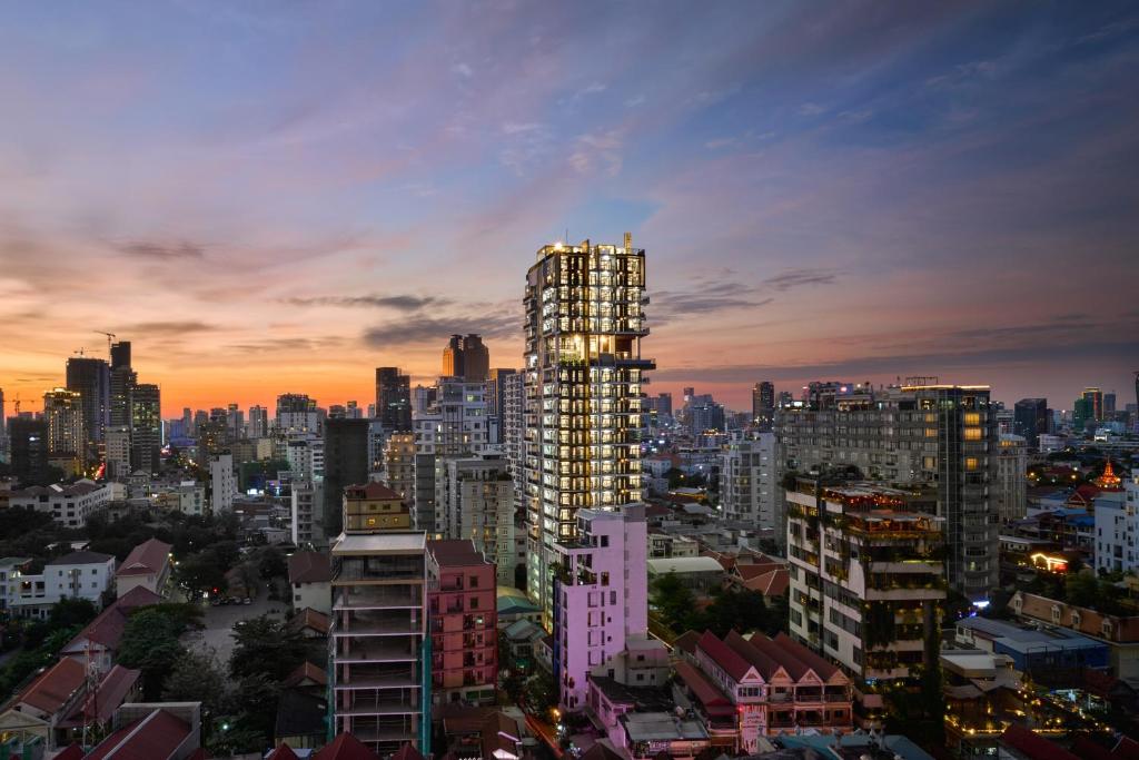 un edificio alto con vistas al horizonte de la ciudad al atardecer en BIJOU Serviced Residence en Phnom Penh