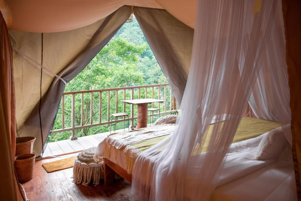 Patjung的住宿－Glamping tent in Pelaga Eco Park，客房设有天蓬床和阳台。