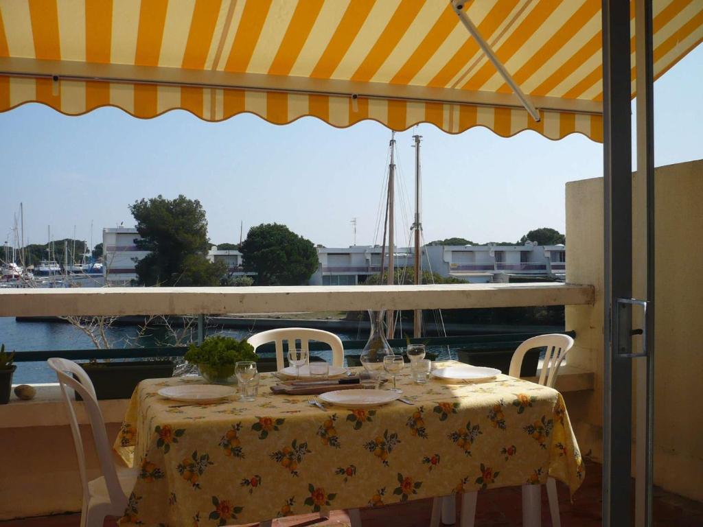 - une table avec des chaises et un parasol sur le balcon dans l'établissement Marina Duplex 4 couchages, Terrasse et Solarium, Clim, Wifi, Parking, Port Camargue - FR-1-250-217, au Grau-du-Roi