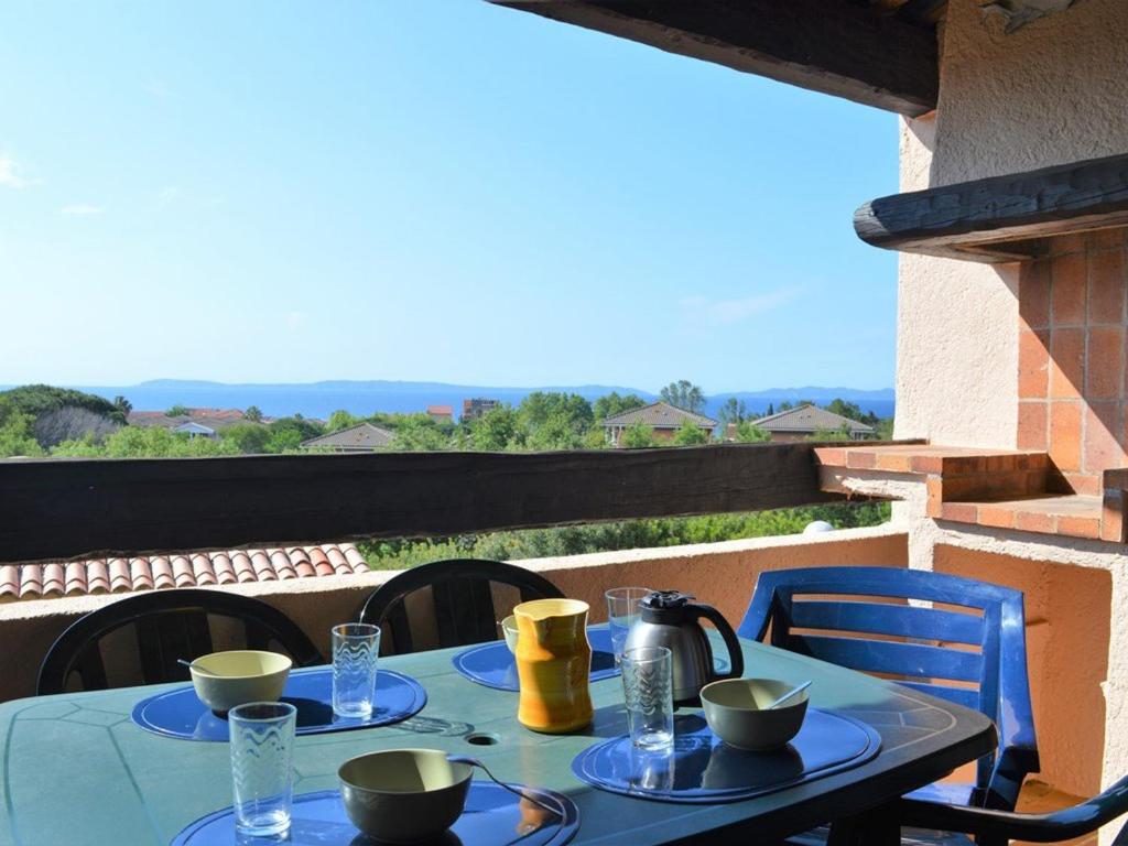 une table bleue avec des bols et des tasses sur un balcon dans l'établissement Appartement 2 pièces avec parking près de la plage - FR-1-251-348, au Lavandou