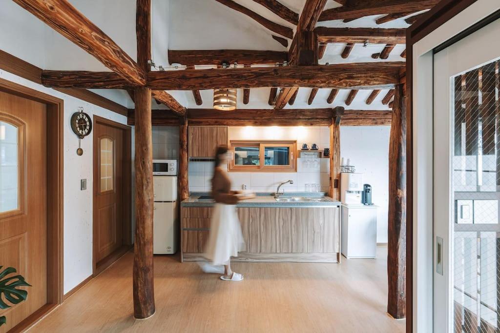 uma mulher está de pé na cozinha de uma casa em Hanokstay Haru em Jeonju