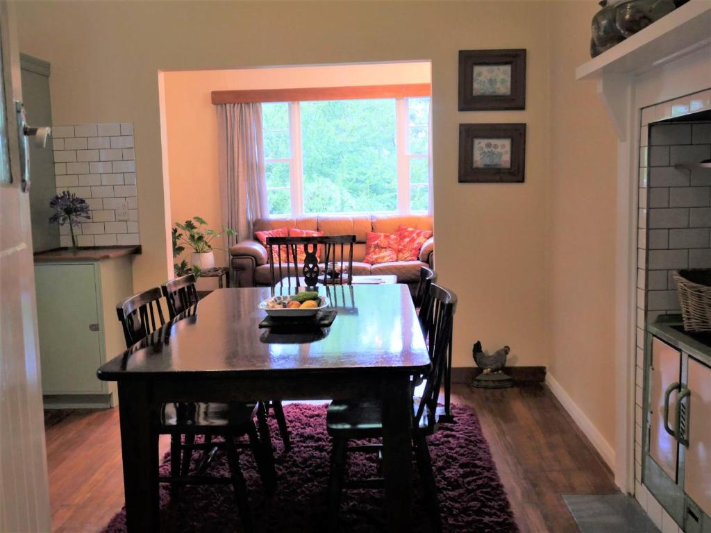 ein Esszimmer mit einem Tisch mit Stühlen und einem Sofa in der Unterkunft Tinui Food Forest Cottage in Whareama