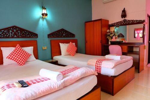 a bedroom with two beds with red and white pillows at โรงแรม พี รีสอร์ท in Kamphaeng Phet