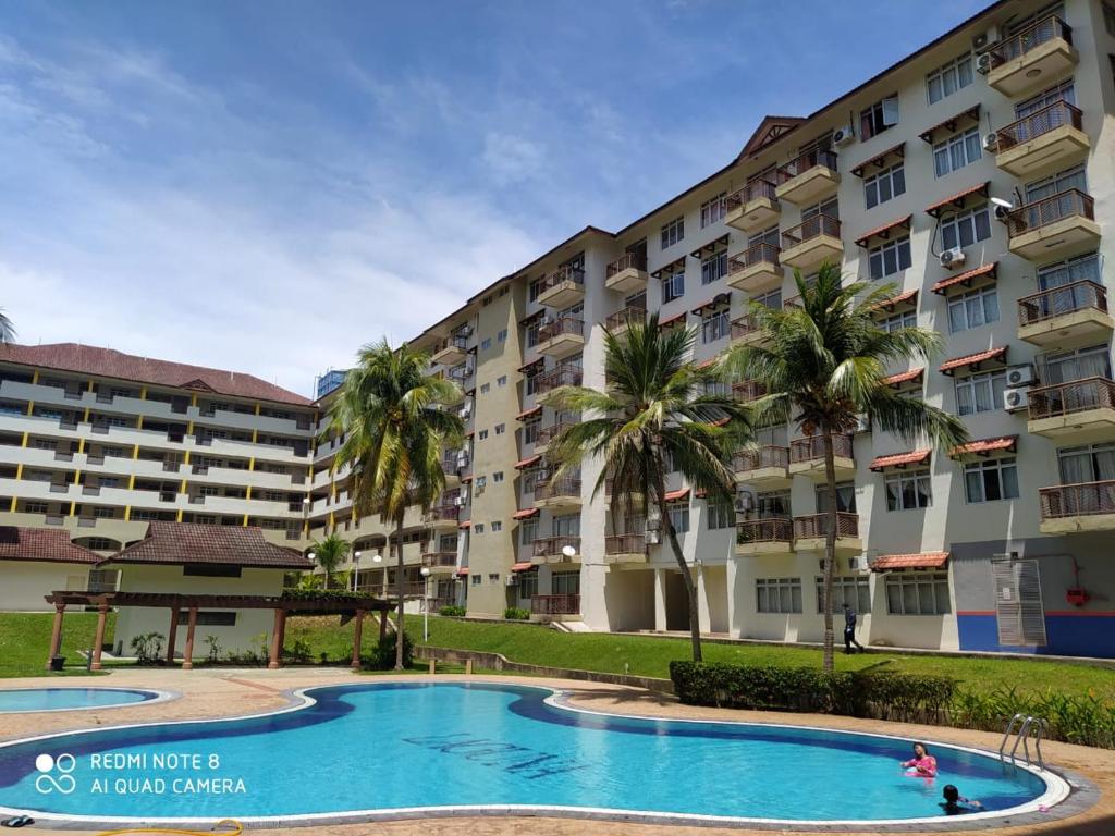 a large apartment building with a swimming pool and palm trees at PD Laguna Homestay Red in Port Dickson