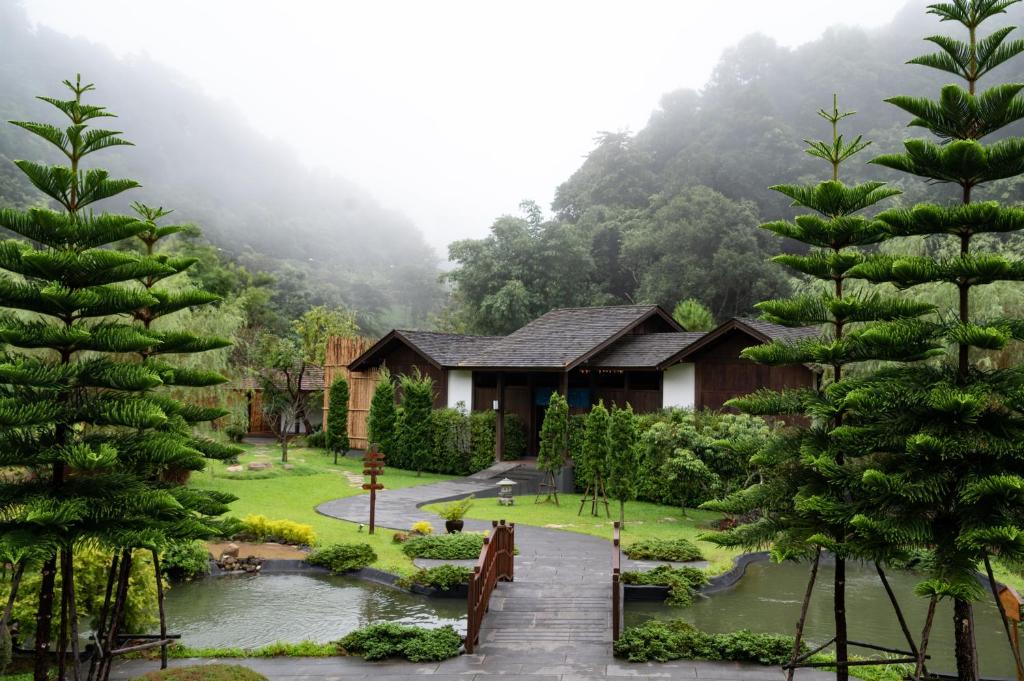 une maison avec un jardin et des arbres devant elle dans l'établissement Onsen at Moncham, à Mae Rim