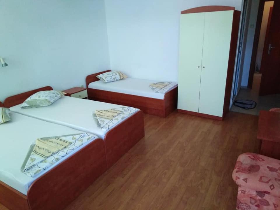 two beds in a room with wooden floors at Къща за гости Стоянови in Primorsko