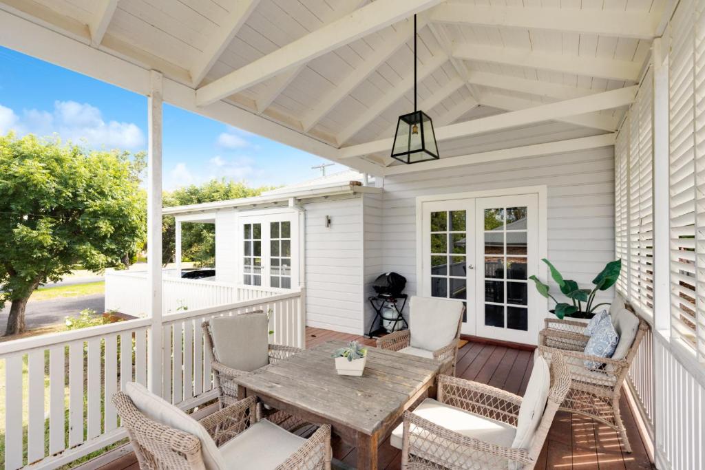 a screened porch with a wooden table and chairs at Modern Hamptons Cottage with Outdoor Deck in Mudgee