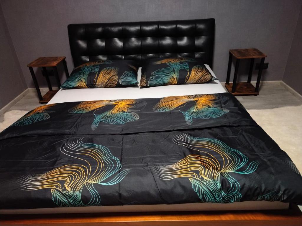 a bed with a black comforter with colorful feathers at Dom Przy Lesie in Istebna