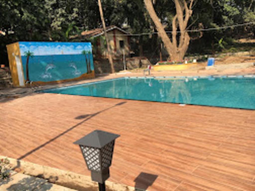 una piscina con un poste de luz al lado en Nature fun resort en Pune