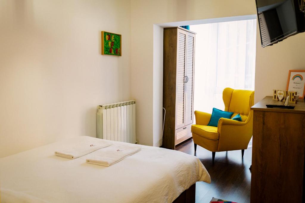 1 dormitorio con 1 cama y 1 silla amarilla en House of colors, en Petroşani