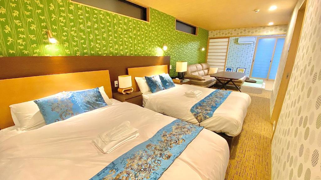 2 camas en una habitación de hotel con papel pintado verde en One More Heart Fushimi Inari, en Momoyama-chō