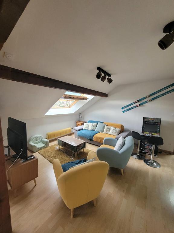 ein Wohnzimmer mit einem Sofa und einem TV in der Unterkunft Le Trésor des Vosges Appartement spacieux et lumineux 80m2 idéal famille 4 à 6 personnes in Gérardmer