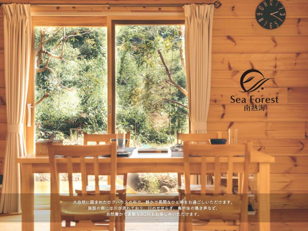een eetkamer met een tafel en stoelen en een raam bij Sea Forest 南熱海 in Atami