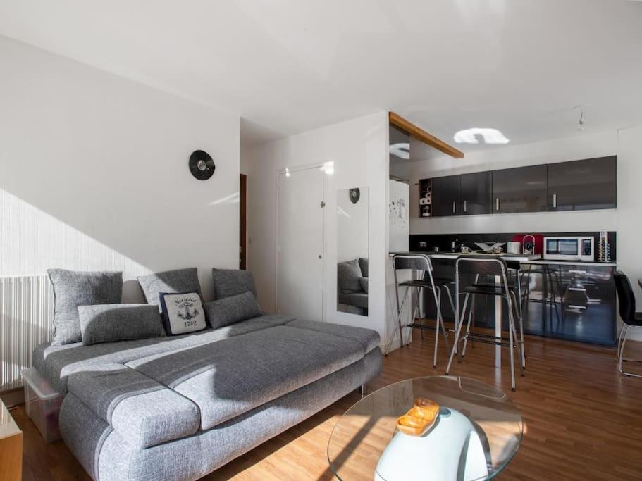 a living room with a gray couch and a kitchen at Proche du port avec balcon - Kerlaouen in Vannes