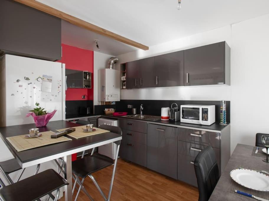 a kitchen with black and red cabinets and a table at Proche du port avec balcon - Kerlaouen in Vannes