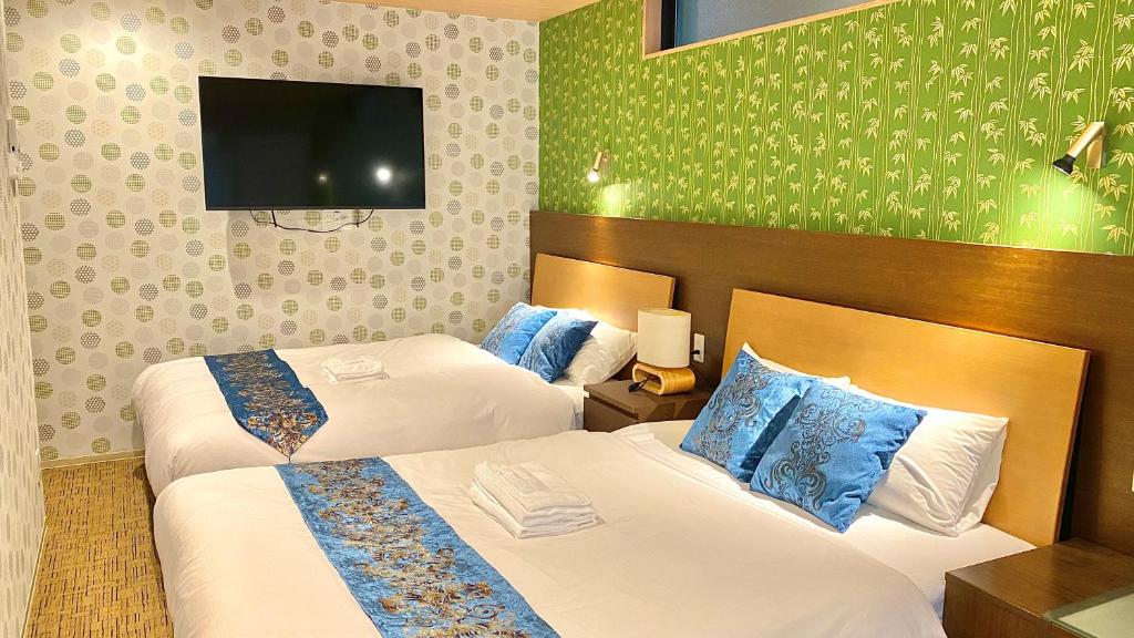 a hotel room with two beds and a flat screen tv at One More Heart Fushimi Inari in Momoyama-chō