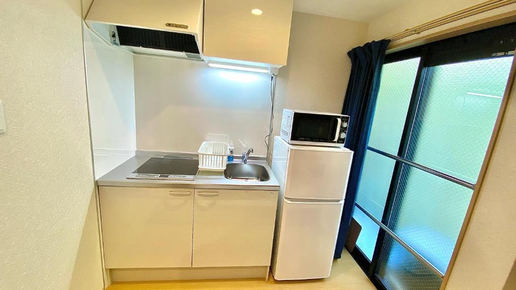 a small kitchen with a refrigerator and a microwave at One More Heart Fushimi Inari in Momoyama-chō