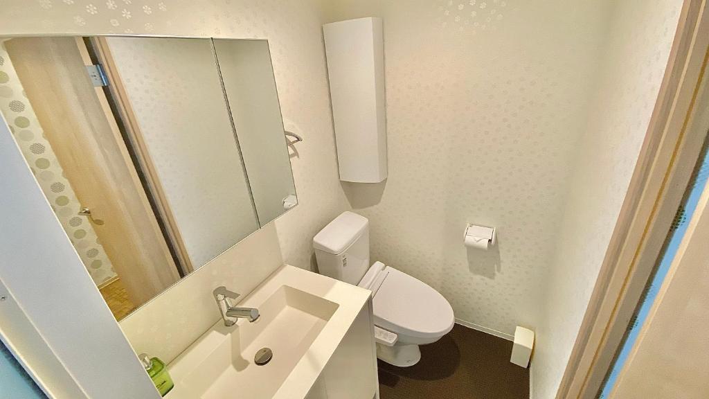 a bathroom with a toilet and a sink and a mirror at One More Heart Fushimi Inari in Momoyama-chō