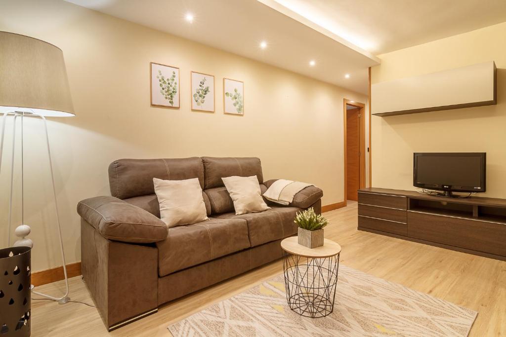 uma sala de estar com um sofá castanho e uma televisão de ecrã plano em Fika apartmento urbano con wifi em Bilbau