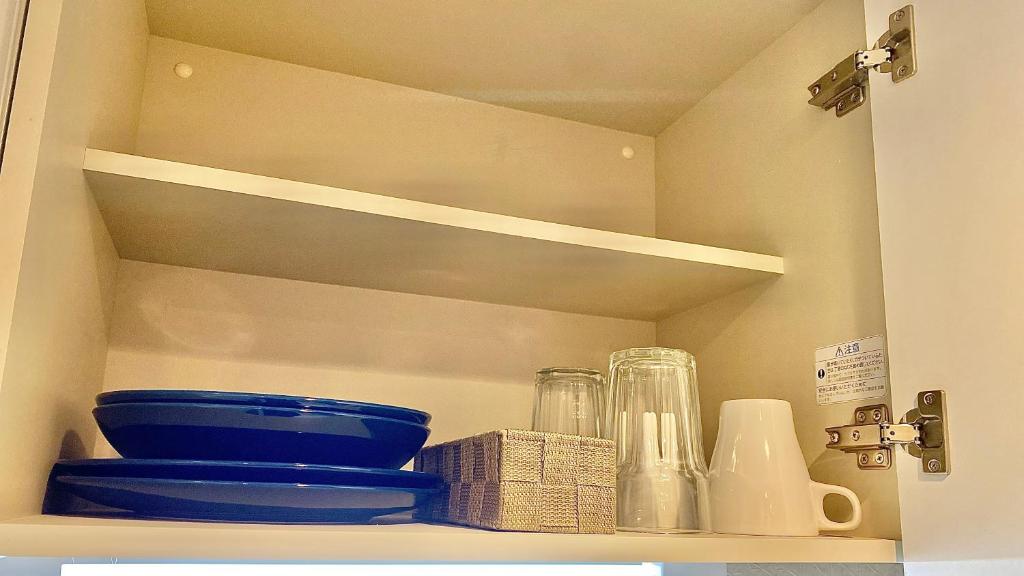 a shelf with bowls and other kitchen items on it at One More Heart Fushimi Inari in Momoyama-chō