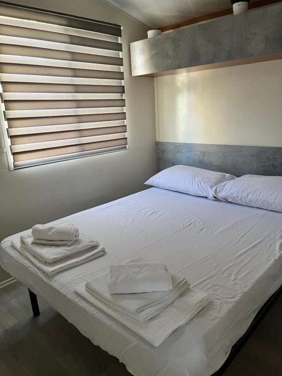 Una cama blanca con toallas en un dormitorio en Dalmacia mobile homes and caravans at the beach, en Privlaka