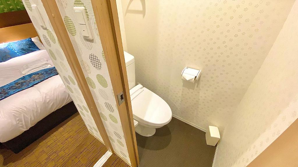 a small bathroom with a toilet and a bed at One More Heart Fushimi Inari in Momoyama-chō