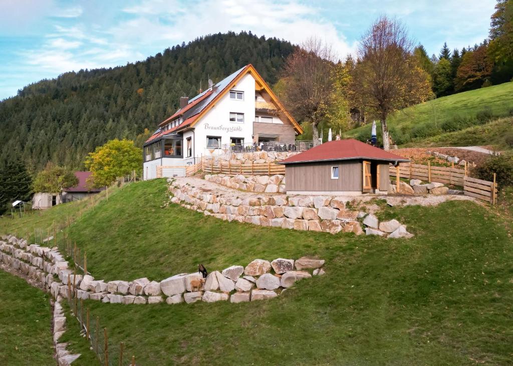 a house on a hill with a stone wall at Berggasthaus Braunbergstüble in Oppenau