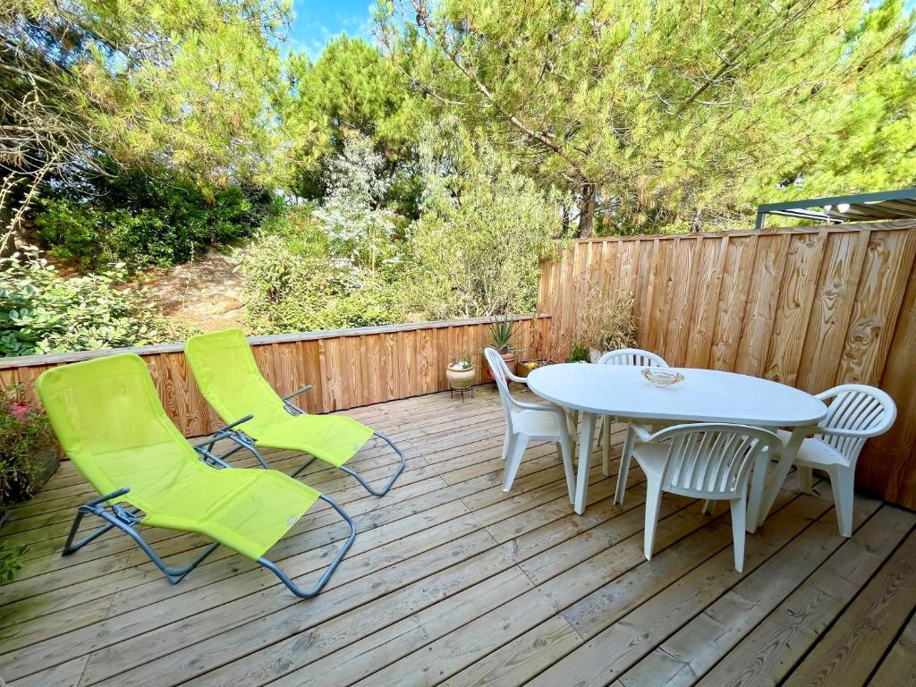 une terrasse en bois avec une table et des chaises. dans l'établissement Niedliche Wohnung mit Terrasse direkt am Strand, à Lège-Cap-Ferret