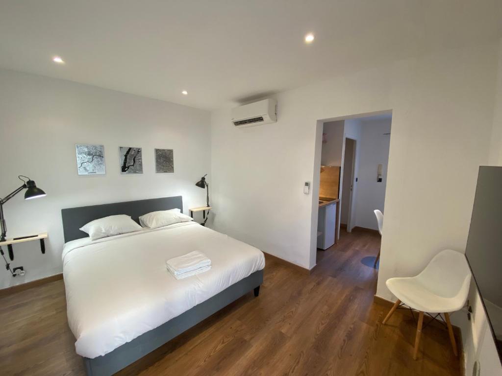 une chambre blanche avec un lit et une chaise dans l'établissement STUDIO CONFORT ROTONDE*CALME*CLIM*WIFI*SMART TV, à Aix-en-Provence
