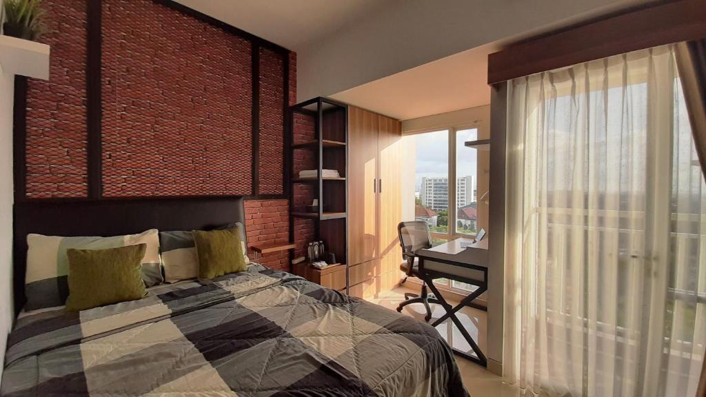 a bedroom with a bed and a desk and a brick wall at Apartemen Taman Melati Sinduadi By NGINAP in Sleman