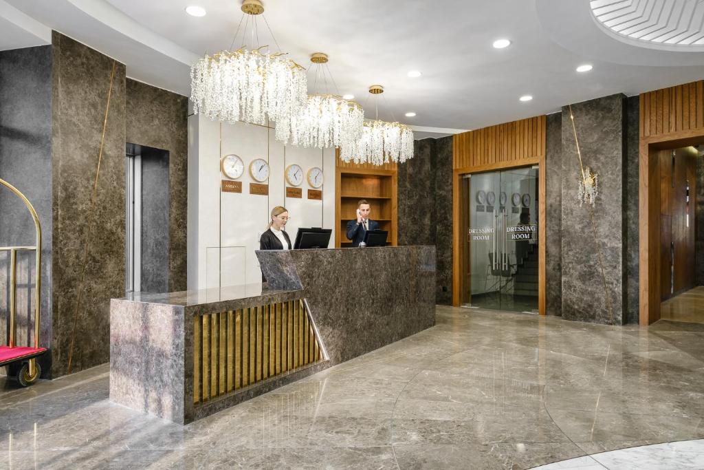 two people sitting at a reception desk in a lobby at Grand Mildom Hotel in Almaty