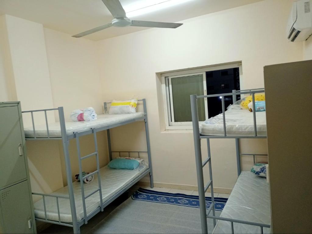 um quarto com 3 beliches e uma janela em SmSma BedSpace Hostel em Ajman
