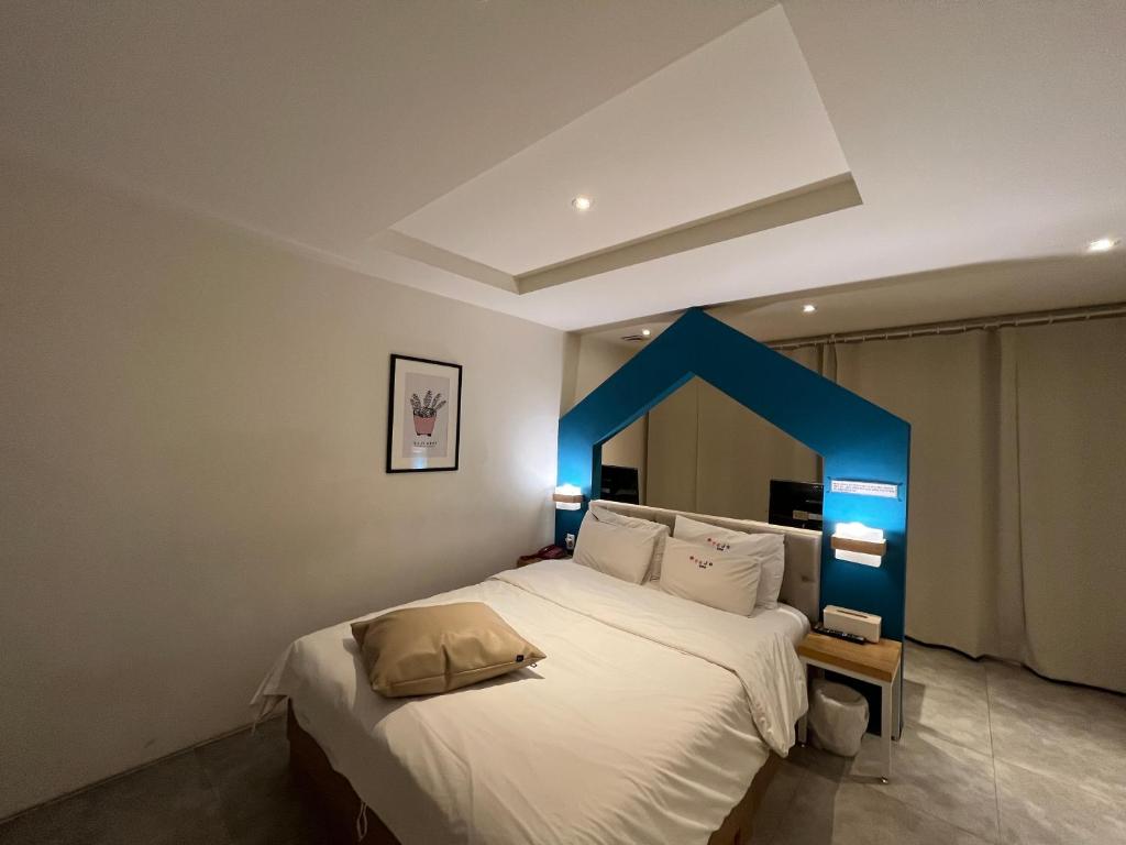 Hotel Yaja Hwajeong Station في غويانغ: غرفة نوم بسرير ابيض كبير بلكنة زرقاء