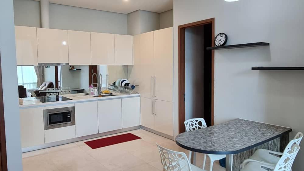 uma cozinha com armários brancos e uma mesa com cadeiras em Soho Suites KLCC by Harry em Kuala Lumpur