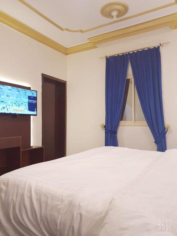 a bedroom with a white bed with a blue curtain at Basma Plaza in Abha